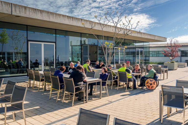 Man sieht Mitarbeiter draußen gemeinsam in der Sonne sitzen.
